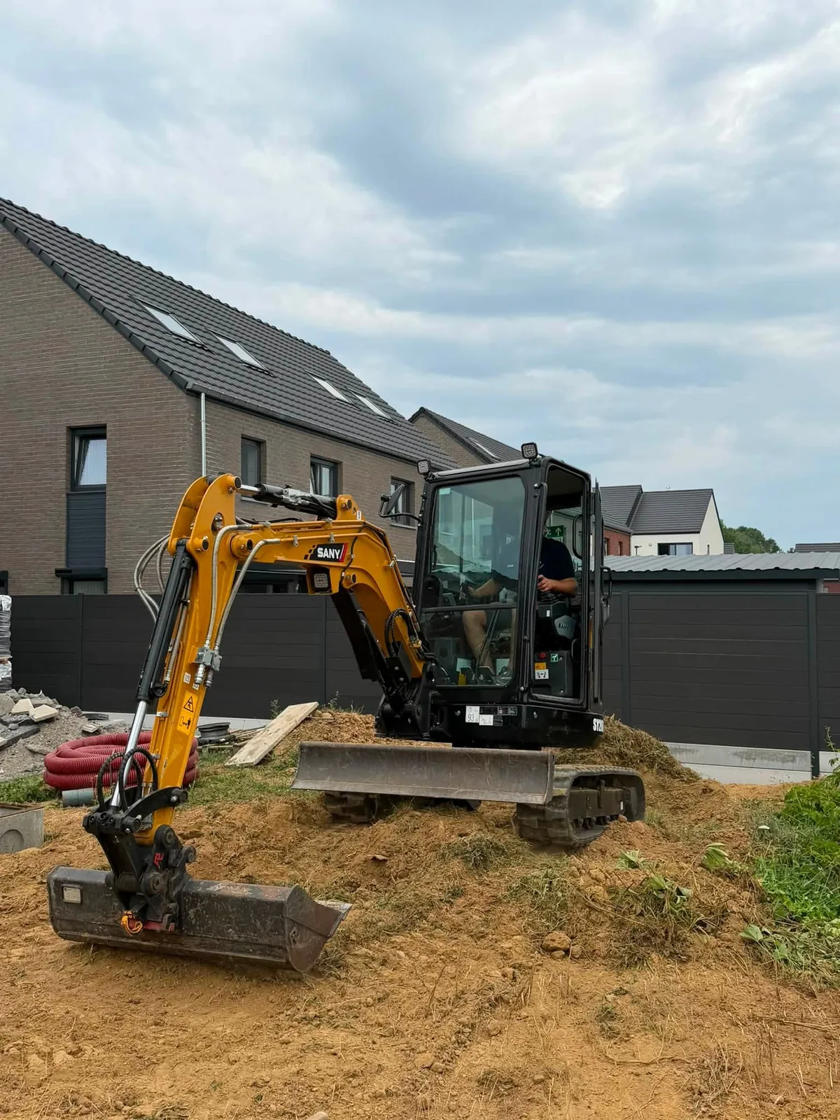 Mini-pelle en terrassement près d'une maison